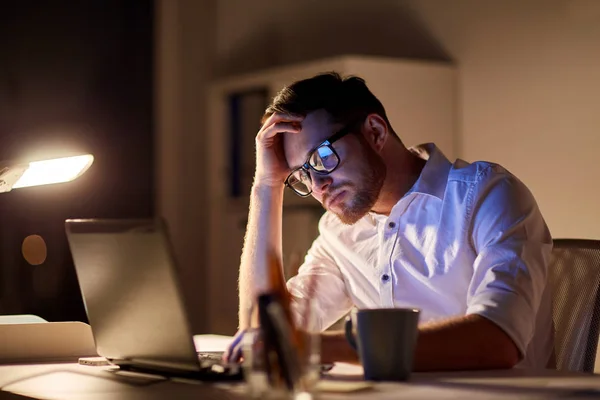 Business man with laptop thinking at night office — стоковое фото