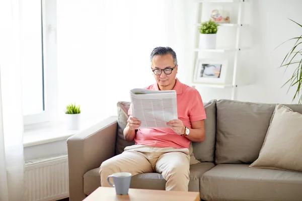 Homem feliz em óculos ler jornal em casa — Fotografia de Stock