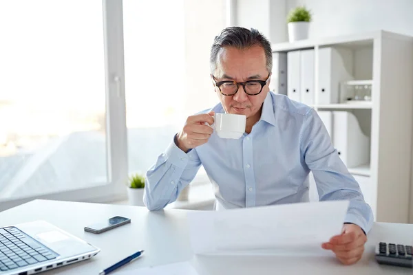 Uomo d'affari con documenti che bevono caffè in ufficio — Foto Stock