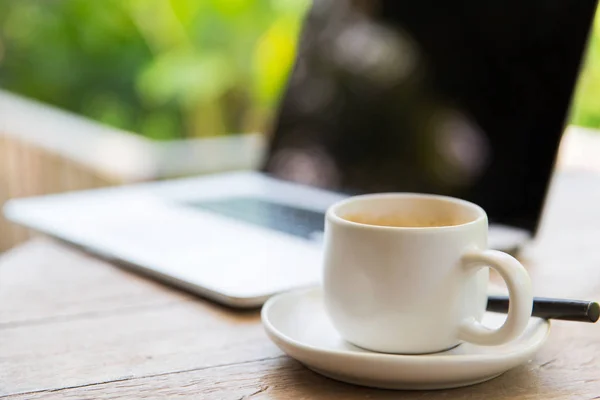 Primer plano de la taza de café y portátil en la mesa — Foto de Stock