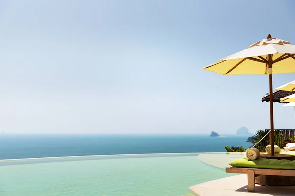 Piscine à débordement avec parasol et chaises longues à l'océan — Photo