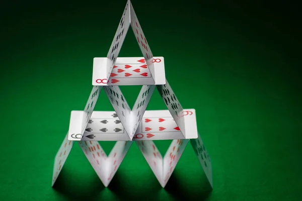 Huis van speelkaarten op groene tabel doek — Stockfoto