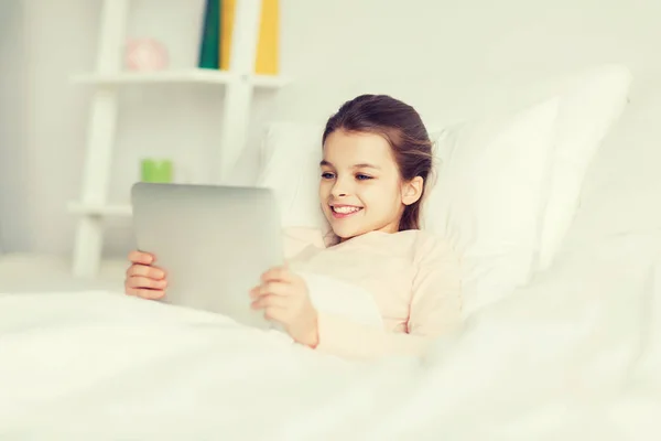 Chica feliz acostada en la cama con la tableta PC en casa —  Fotos de Stock