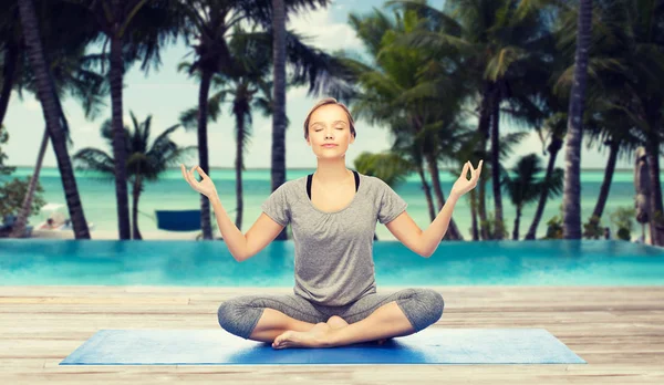 Mujer haciendo meditación de yoga en pose de loto en la estera — Foto de Stock
