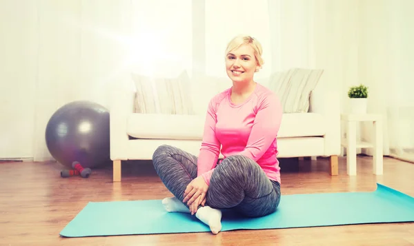 Happy woman sitting on mat at home — Stock Photo, Image