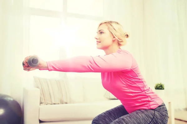 Leende kvinna med hantlar tränar hemma — Stockfoto