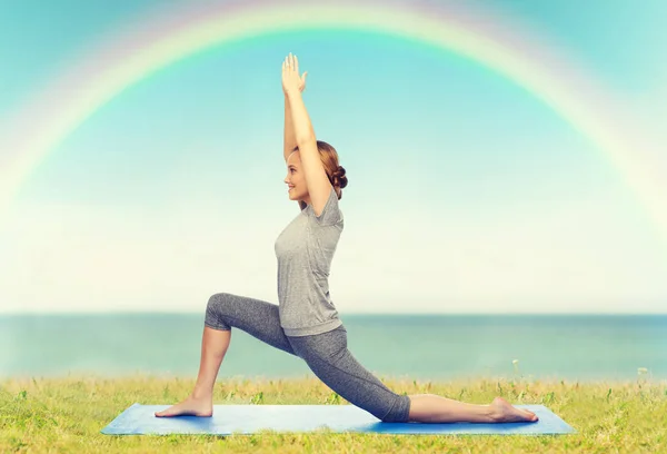 Lycklig kvinna att göra yoga i låg utfall på matta — Stockfoto