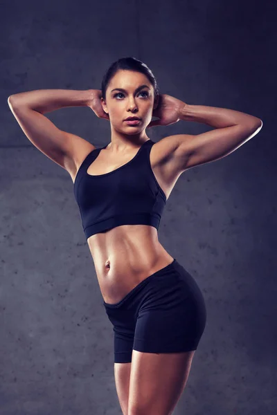 Молодая женщина позирует и показывает мышцы в спортзале — стоковое фото