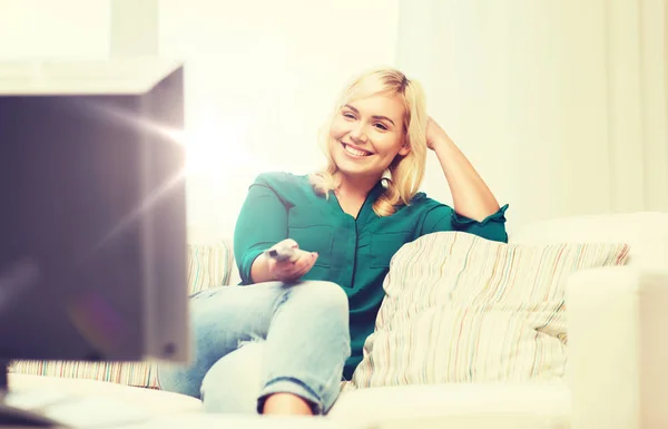 Χαμογελαστή γυναίκα με απομακρυσμένη παρακολουθώντας τηλεόραση στο σπίτι — Φωτογραφία Αρχείου