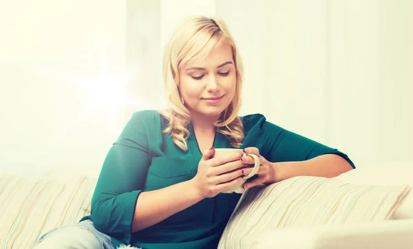 Glad kvinna med kopp te eller kaffe hemma — Stockfoto