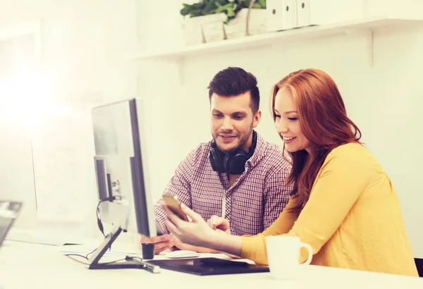 Lächelndes Kreativteam mit Smartphones im Büro — Stockfoto