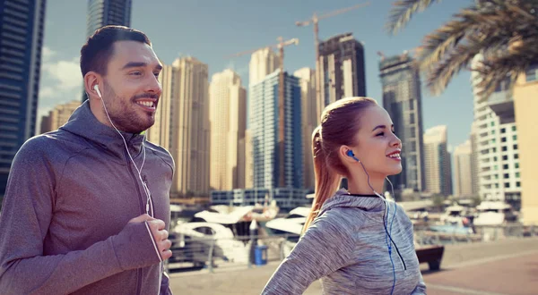 幸福的夫妇带着耳机在城市中运行 — 图库照片