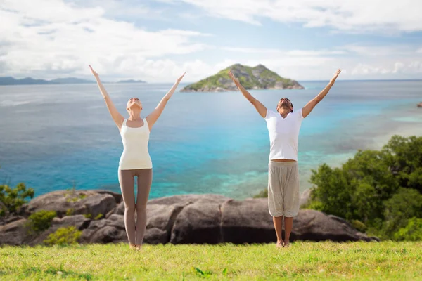 Glückliches Paar macht Yoga-Übungen am Strand — Stockfoto