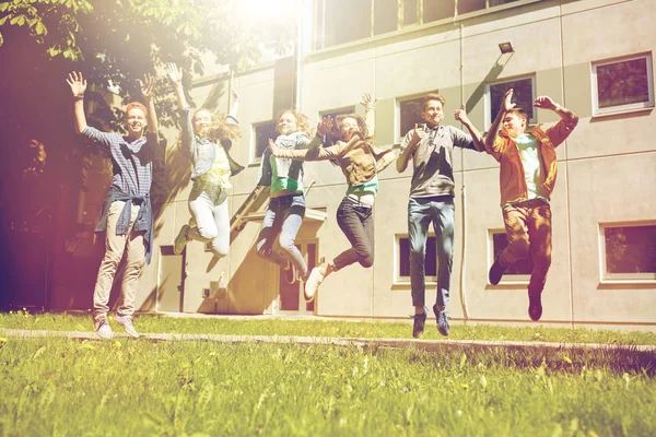 Happy teenage students or friends jumping outdoors — Stock Photo, Image