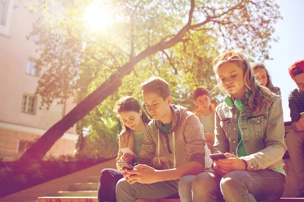 Группа друзей-подростков со смартфонами на открытом воздухе — стоковое фото