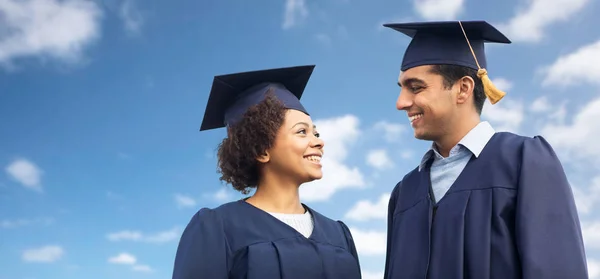 Happy students or bachelors in mortar boards — Stock Photo, Image