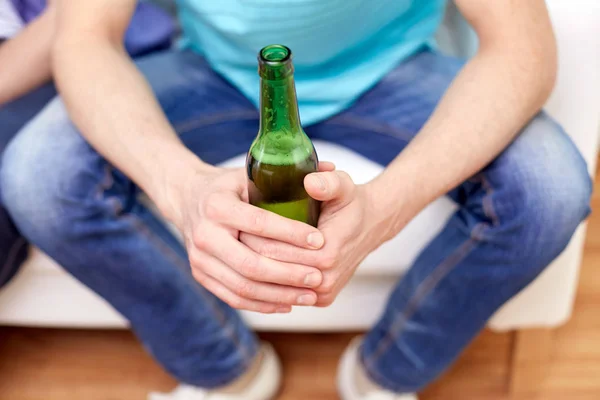 Homens com garrafas de cerveja sentados no sofá em casa — Fotografia de Stock