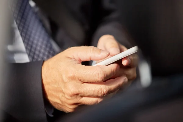 Sénior hombre de negocios mensajes de texto en el teléfono inteligente en coche — Foto de Stock