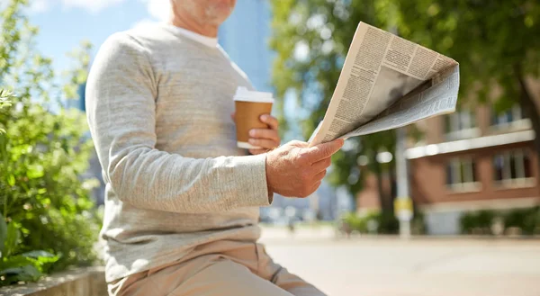 Senior man met koffie lezen krant buiten — Stockfoto