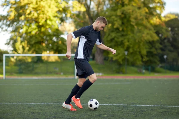 Футболист, играющий с мячом на футбольном поле — стоковое фото