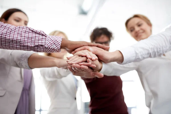 Feliz equipo de negocios con las manos en la parte superior en la oficina —  Fotos de Stock