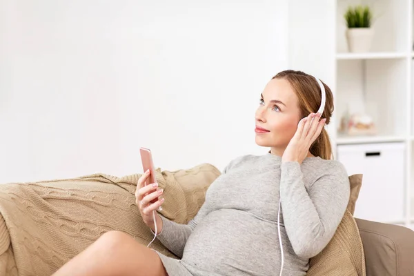 Schwangere mit Smartphone und Kopfhörer — Stockfoto