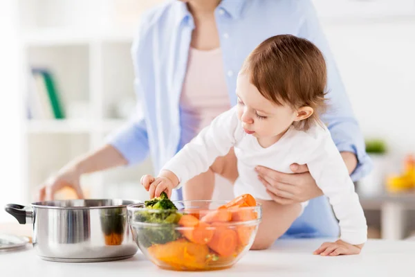 幸せな母と赤ちゃんが自宅に野菜を料理 — ストック写真