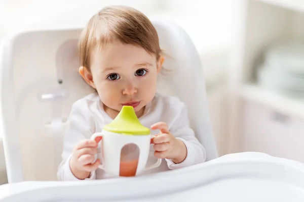 赤ちゃんは、ハイチェア自宅でカップを口から飲む — ストック写真