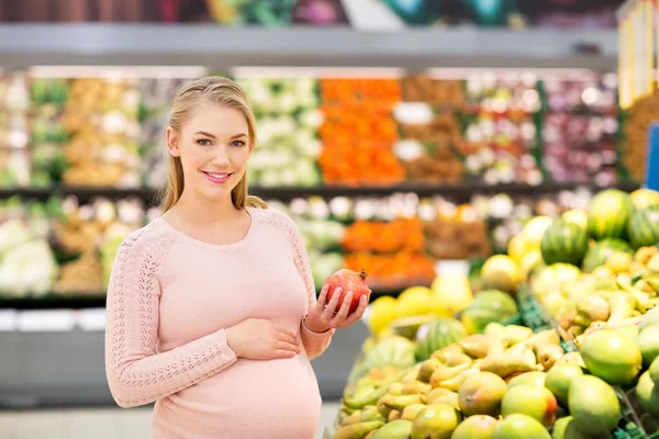 Mujer embarazada feliz con granada en el supermercado — Foto de Stock