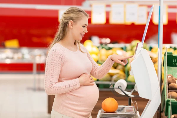 Kobieta w ciąży z grejpfruta w skali o sklep spożywczy — Zdjęcie stockowe