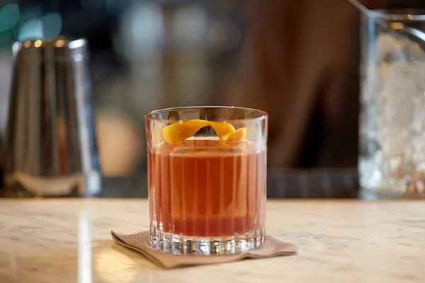 Glas cocktail met sinaasappelschil aan de bar — Stockfoto