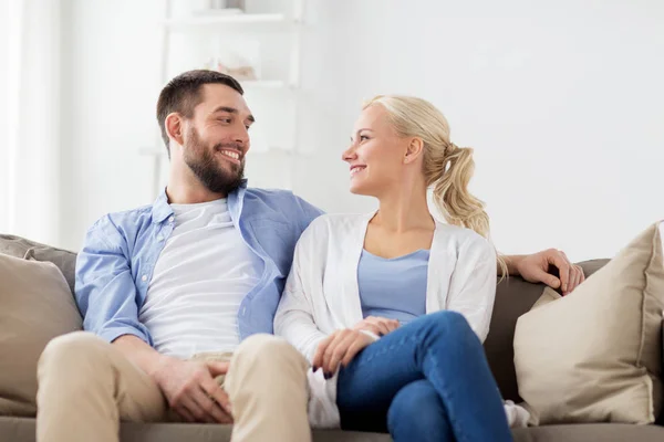 Sonriente feliz pareja sentado en sofá en casa — Foto de Stock