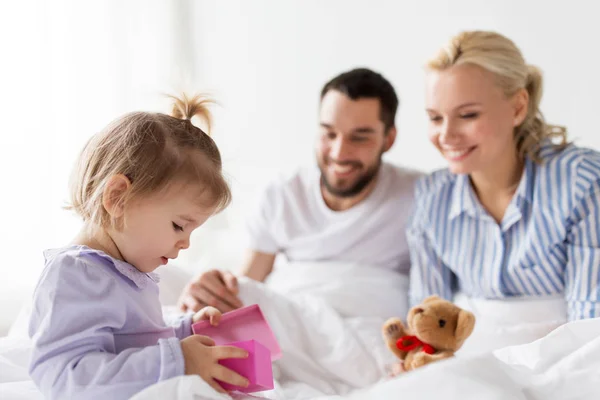 Famiglia felice con scatola regalo a letto a casa — Foto Stock