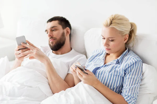 Couple avec smartphones dans le lit à la maison — Photo