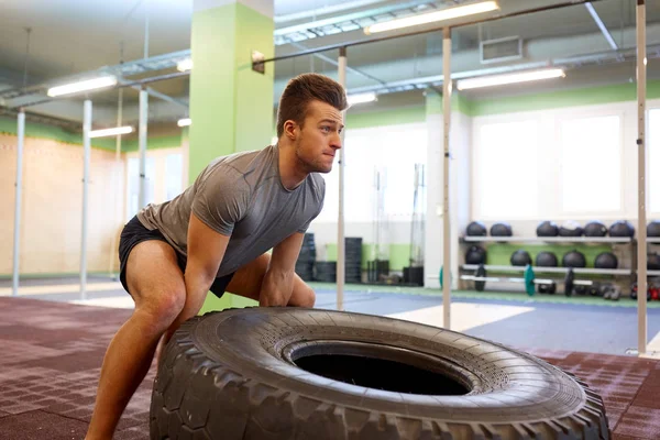 Hombre haciendo fuerte neumático voltear el entrenamiento en el gimnasio — Foto de Stock