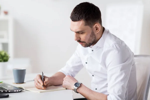 Empresário escrevendo para notebook no escritório — Fotografia de Stock