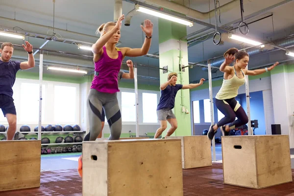 Grupo de personas haciendo ejercicios de salto de caja en el gimnasio Fotos de stock