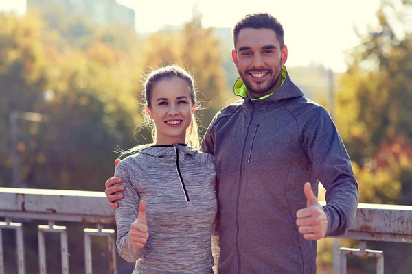 Smiling couple showing thumbs up outdoors — Stock Photo, Image