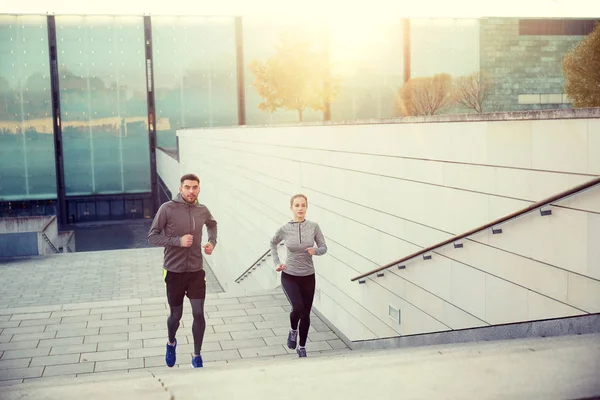 Happy couple running upstairs on city stairs — Stock Photo, Image