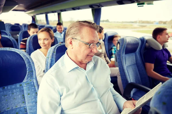 Щасливий старший чоловік читає газету в туристичному автобусі — стокове фото