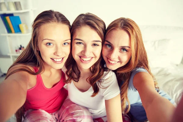 Счастливые друзья или девочки-подростки, делающие селфи дома — стоковое фото