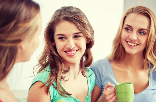 Happy young women drinking tea with sweets at home — Stock Photo, Image