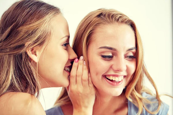 Mujeres jóvenes felices susurrando chismes en casa —  Fotos de Stock