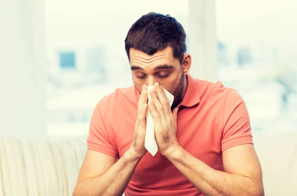 Chory człowiek dmuchanie nosa do serwetki w domu — Zdjęcie stockowe