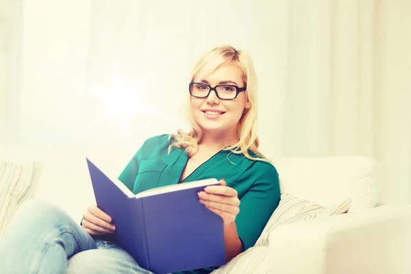 Giovane donna in occhiali lettura libro a casa — Foto Stock