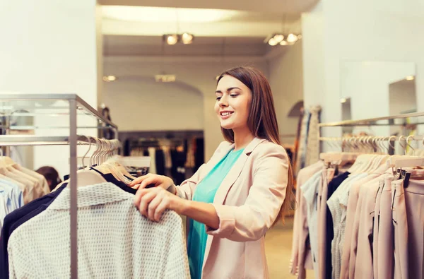 Щаслива молода жінка вибирає одяг у торговому центрі — стокове фото
