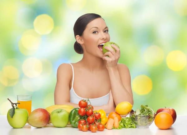 Женщина с фруктами и овощами едят яблоко — стоковое фото