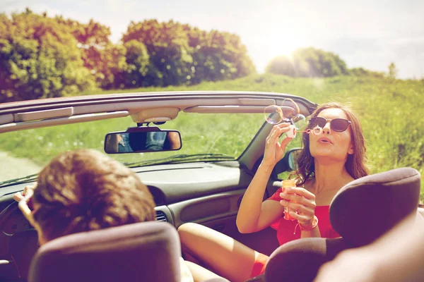 Friends driving in car and blowing bubbles — Stock Photo, Image