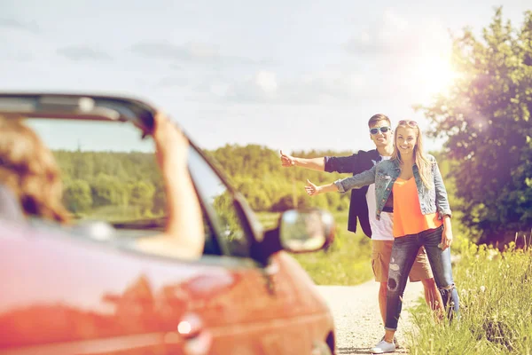 Pareja autostop y parada de coche en el campo — Foto de Stock