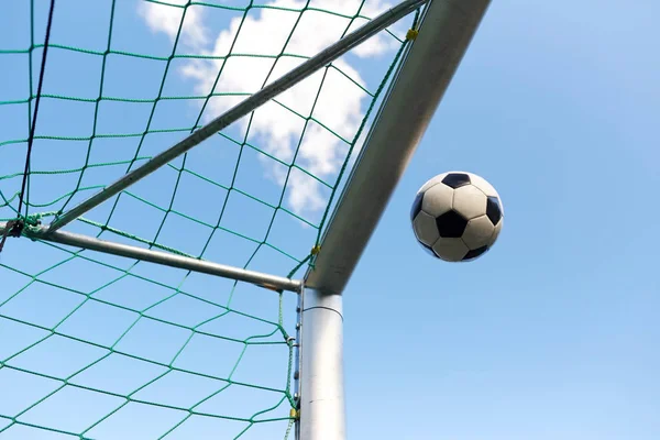 Bola de futebol voando em futebol gol net sobre o céu — Fotografia de Stock